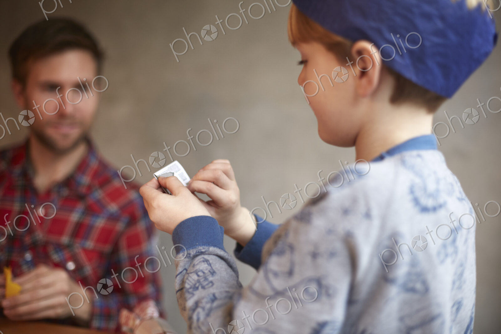 A man and a child seated at a kitchen table sharing a cracker joke.
