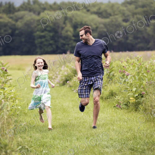 A man and a young child running through a wildflower meadow. A man and a young child running through a wildflower meadow.