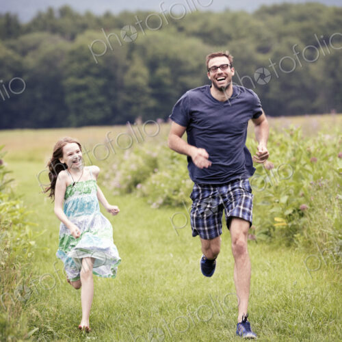 A man and a young child running through a wildflower meadow. A man and a young child running through a wildflower meadow.