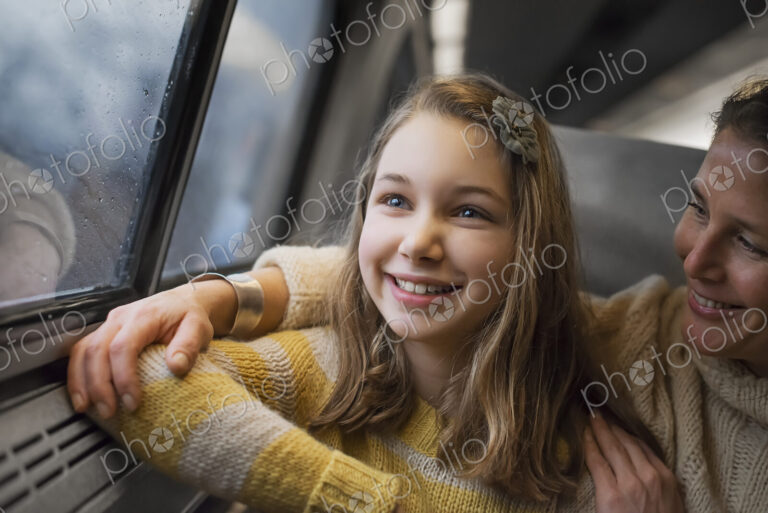 A man and a young girl sitting beside the window in a train carriage looking out at…