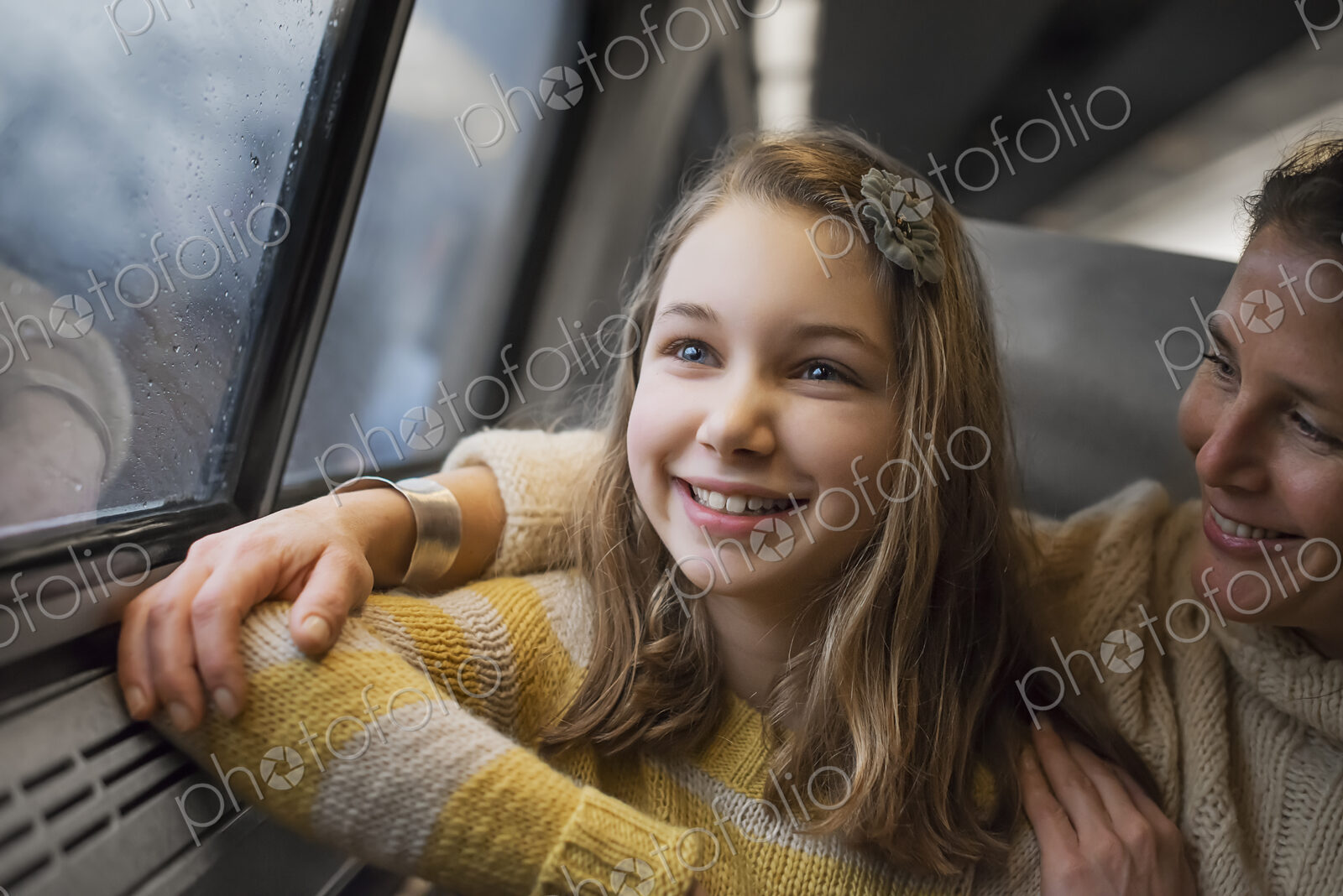 A man and a young girl sitting beside the window in a train carriage looking out at…