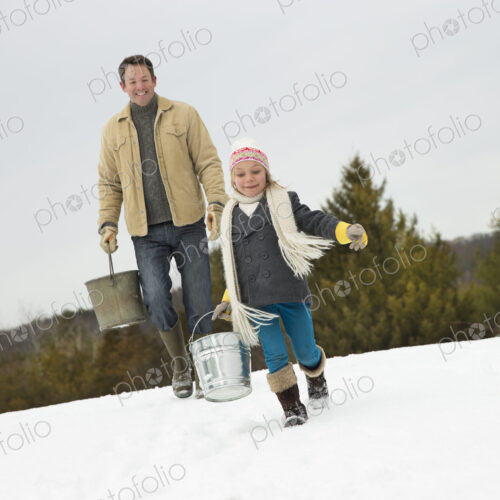 A man and child carrying buckets, running through the snow. A man and child carrying buckets, running through the snow.