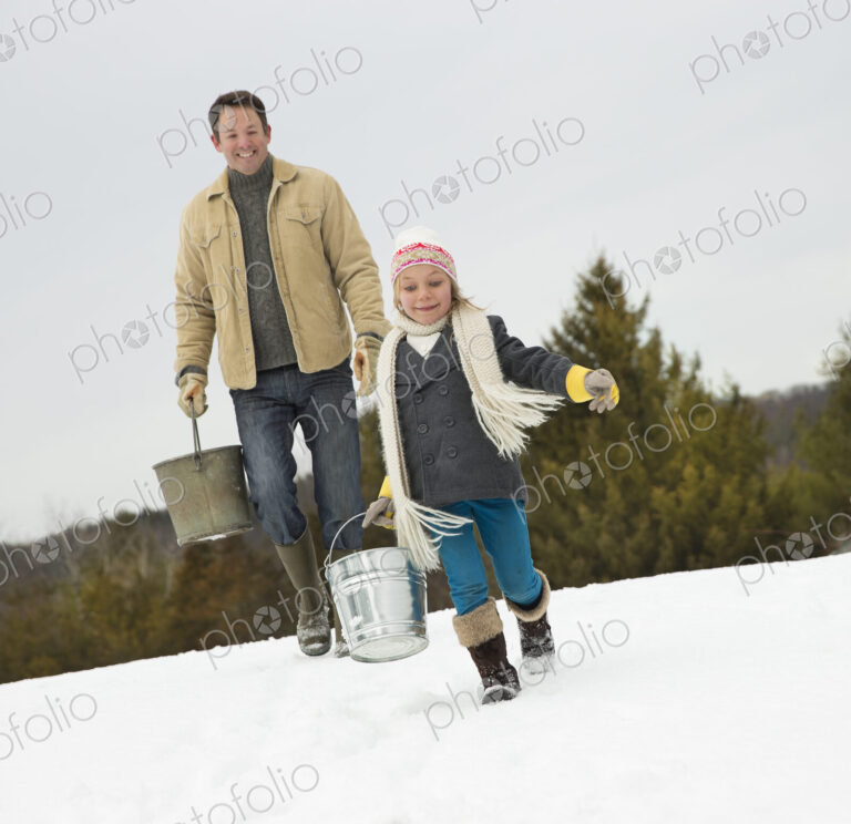 A man and child carrying buckets, running through the snow.