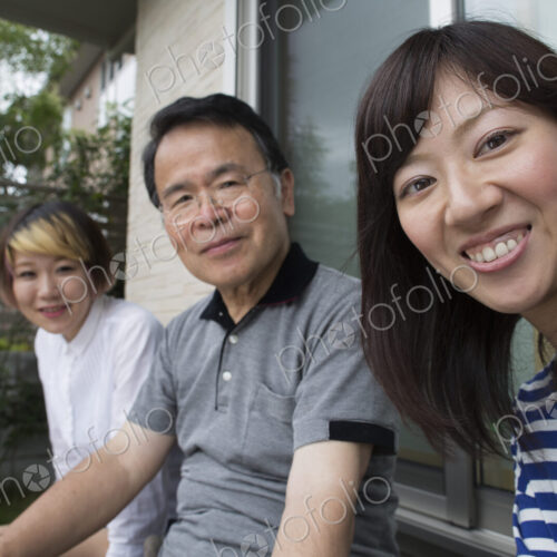 A man and two women sitting at home in a garden. A father and two daughters. A man and two women sitting at home in a garden. A father and two daughters.