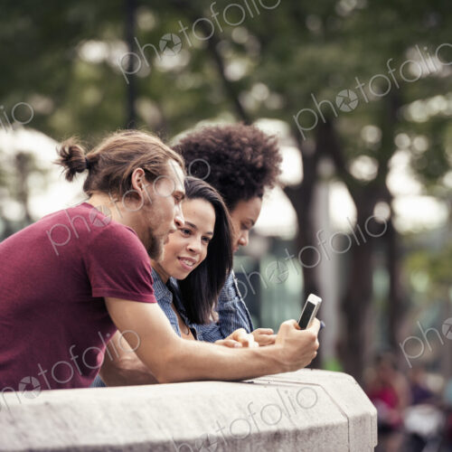 A man and two women using smart phones standing in a park A man and two women using smart phones standing in a park