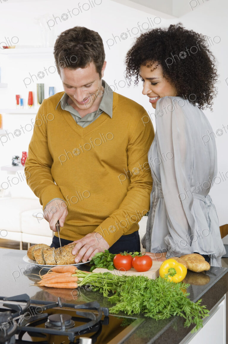 A man and woman, a couple in a kitchen preparing fresh vegetables.