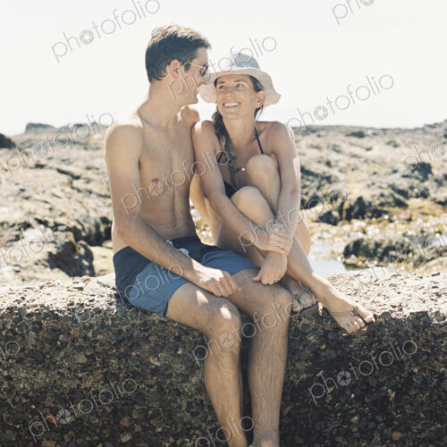 A man and woman, a couple sitting on the beachl looking lovingly at each other A man and woman, a couple sitting on the beachl looking lovingly at each other