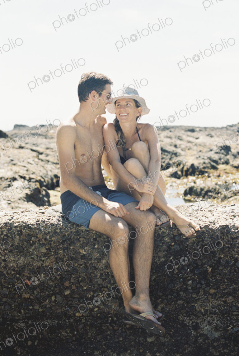 A man and woman, a couple sitting on the beachl looking lovingly at each other