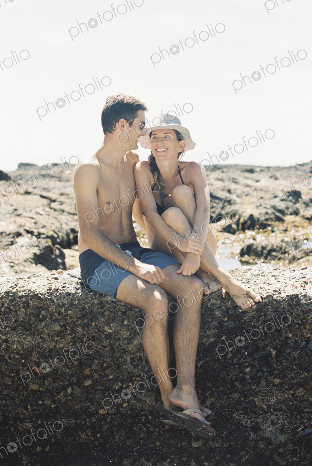 A man and woman, a couple sitting on the beach looking lovingly at each other