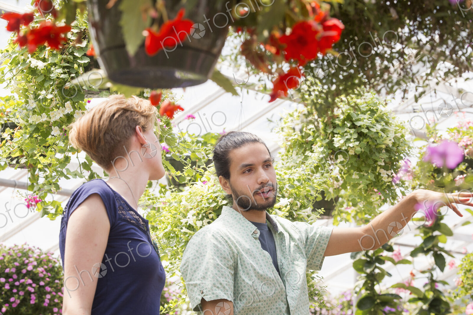 A man and woman looking at colourful flowering plants in a garden centre.