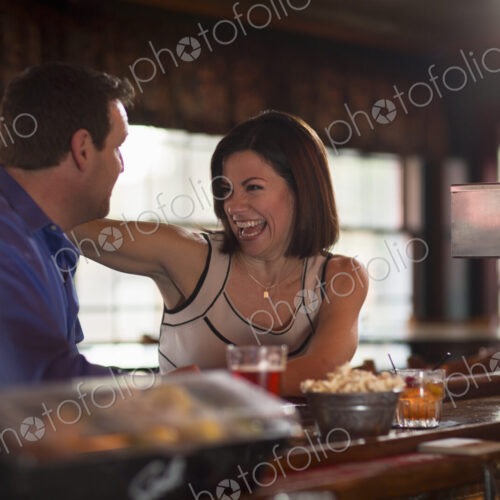 A man and woman seated at a bar, flirting and talking. On a date.