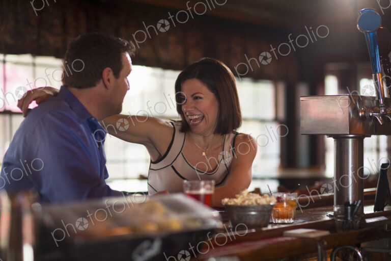 A man and woman seated at a bar, flirting and talking. On a date.