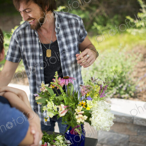 A man and woman standing by a table and a large vase of flowers. A man and woman standing by a table and a large vase of flowers.