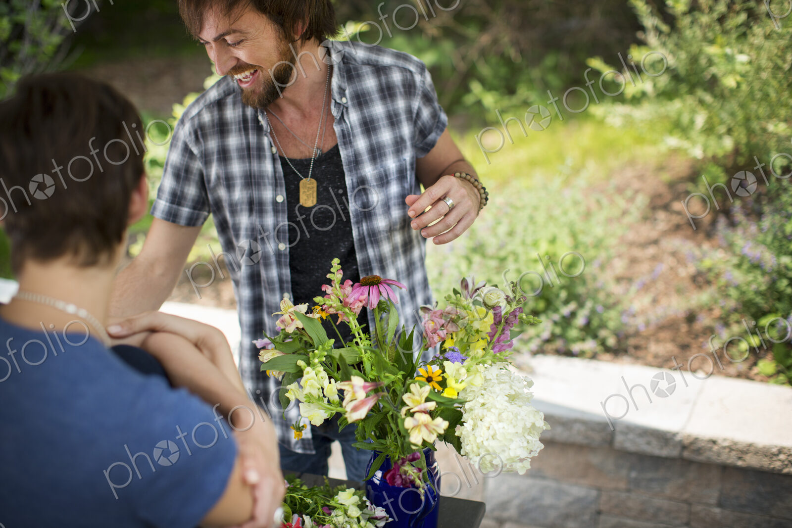 A man and woman standing by a table and a large vase of flowers.