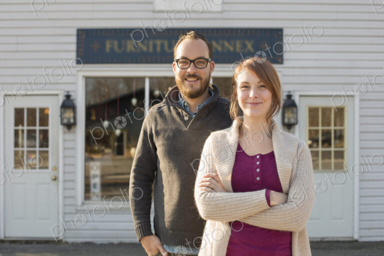 A man and woman standing outside a storefront on a street. A couple running an antique…