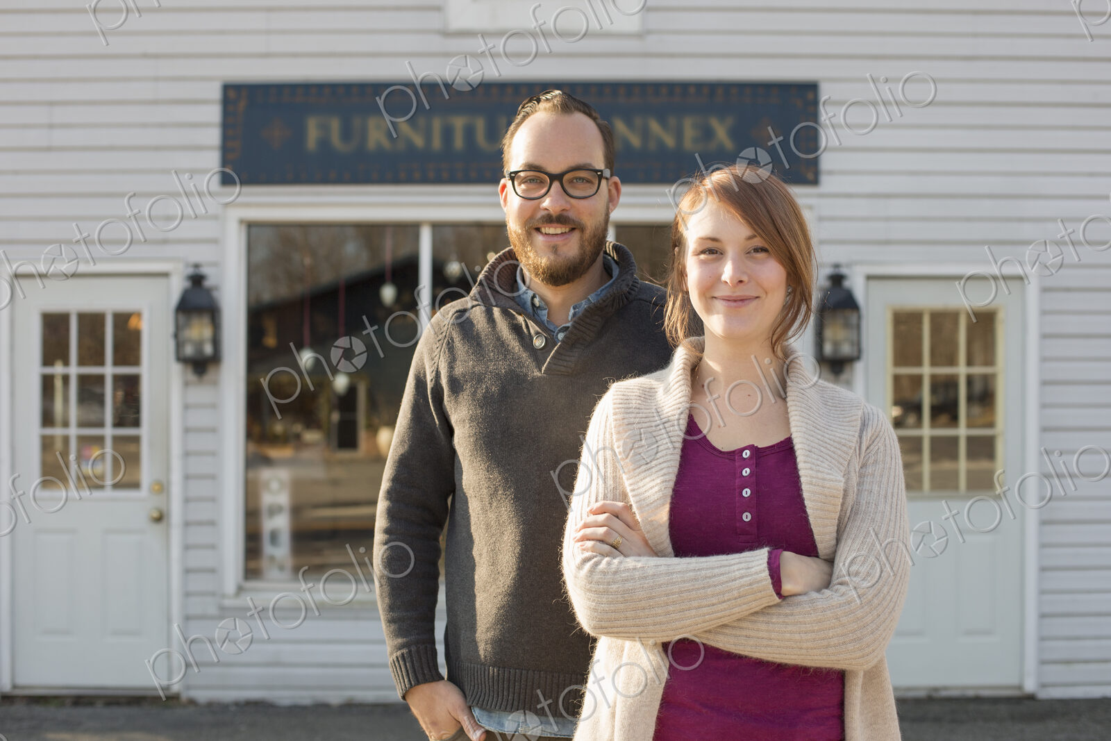 A man and woman standing outside a storefront on a street. A couple running an antique…