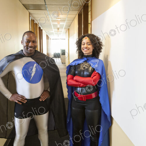 A man and woman team of black office super hero's standing in a hallway of thier office.