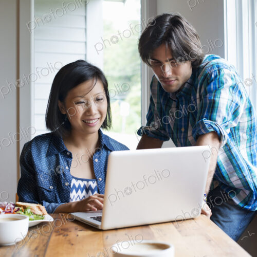A man and woman using a laptop computer in a cafe. A man and woman using a laptop computer in a cafe.