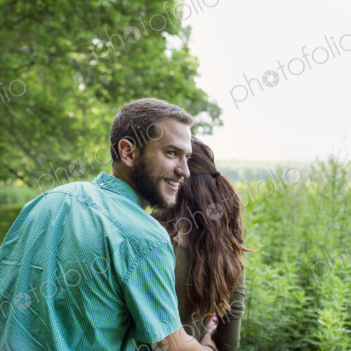 A man and woman walking through a meadow, through the long grass on a summer day.