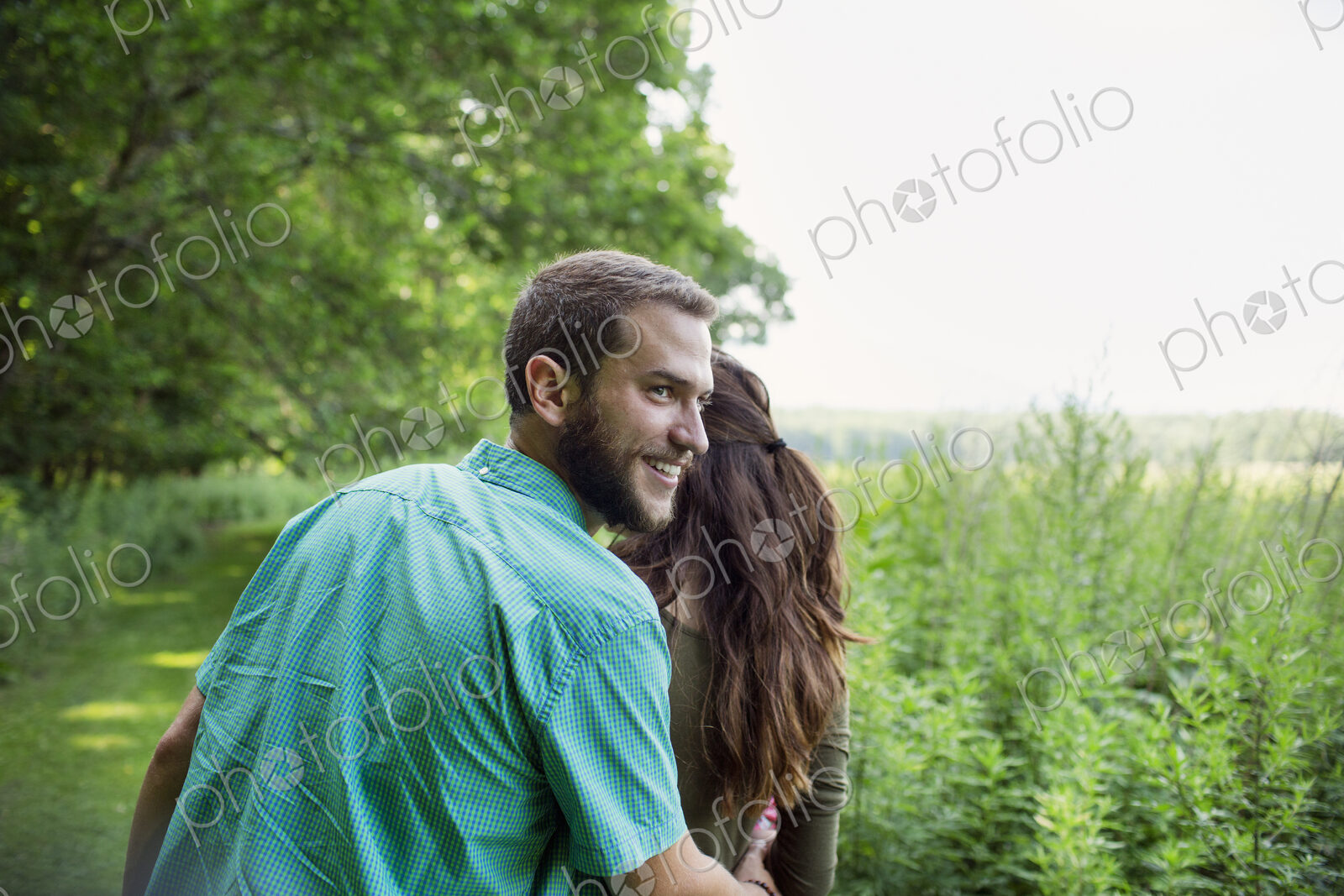 A man and woman walking through a meadow, through the long grass on a summer day.