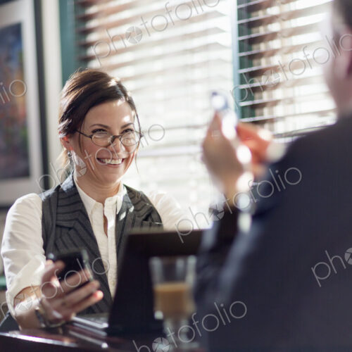 A man and woman working over lunch, seated at their desks. Smiling at each other, and…