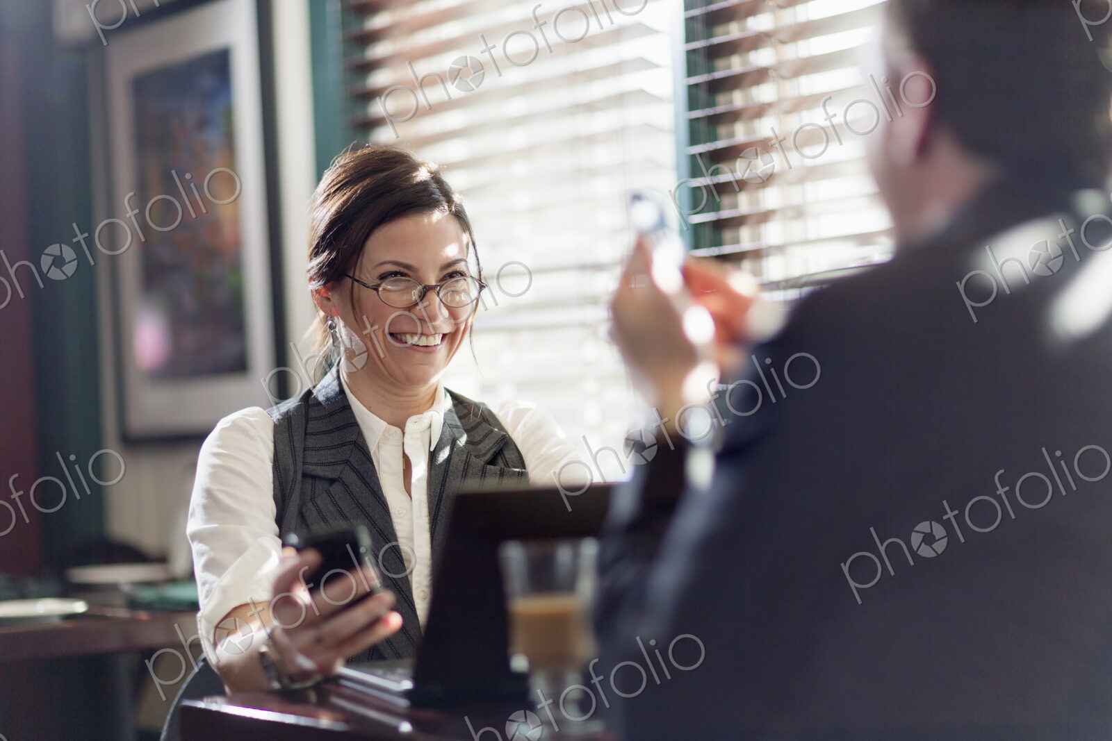 A man and woman working over lunch, seated at their desks. Smiling at each other, and…