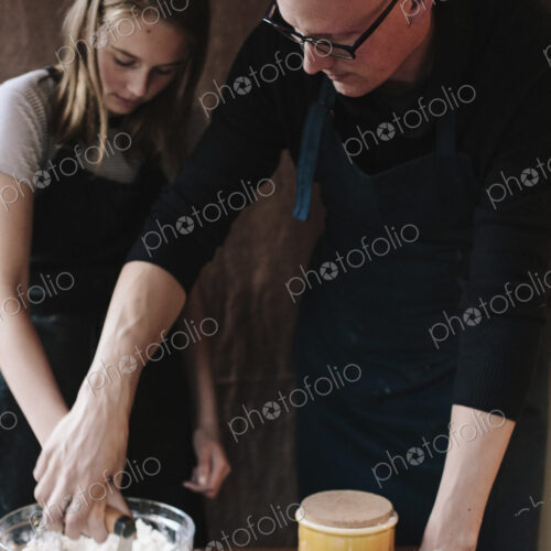 A man and young girl mixing ingredients in a glass bown on a kitchen table.