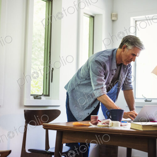 A man at home using a laptop on a desk.