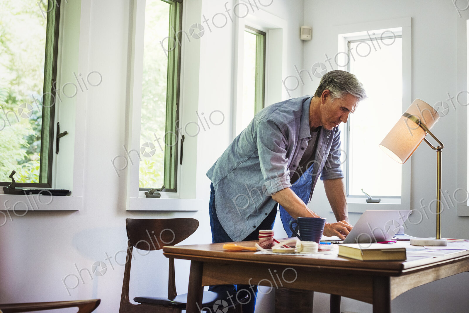 A man at home using a laptop on a desk.