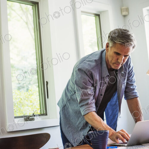 A man at home using a laptop on a desk.