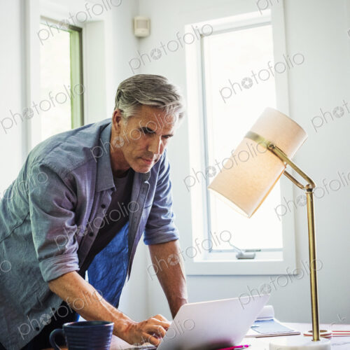 A man at home using a laptop on a desk.