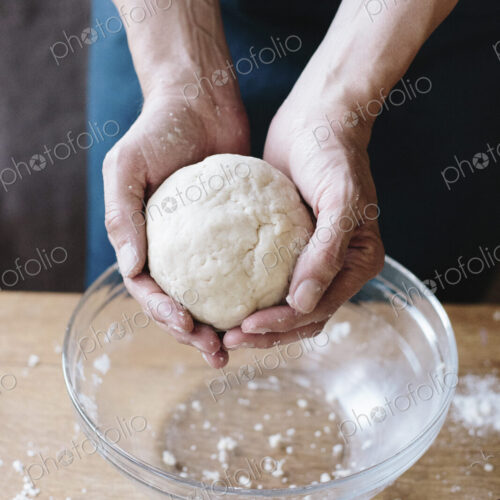 A man baking, holding pastry dough in his hands.