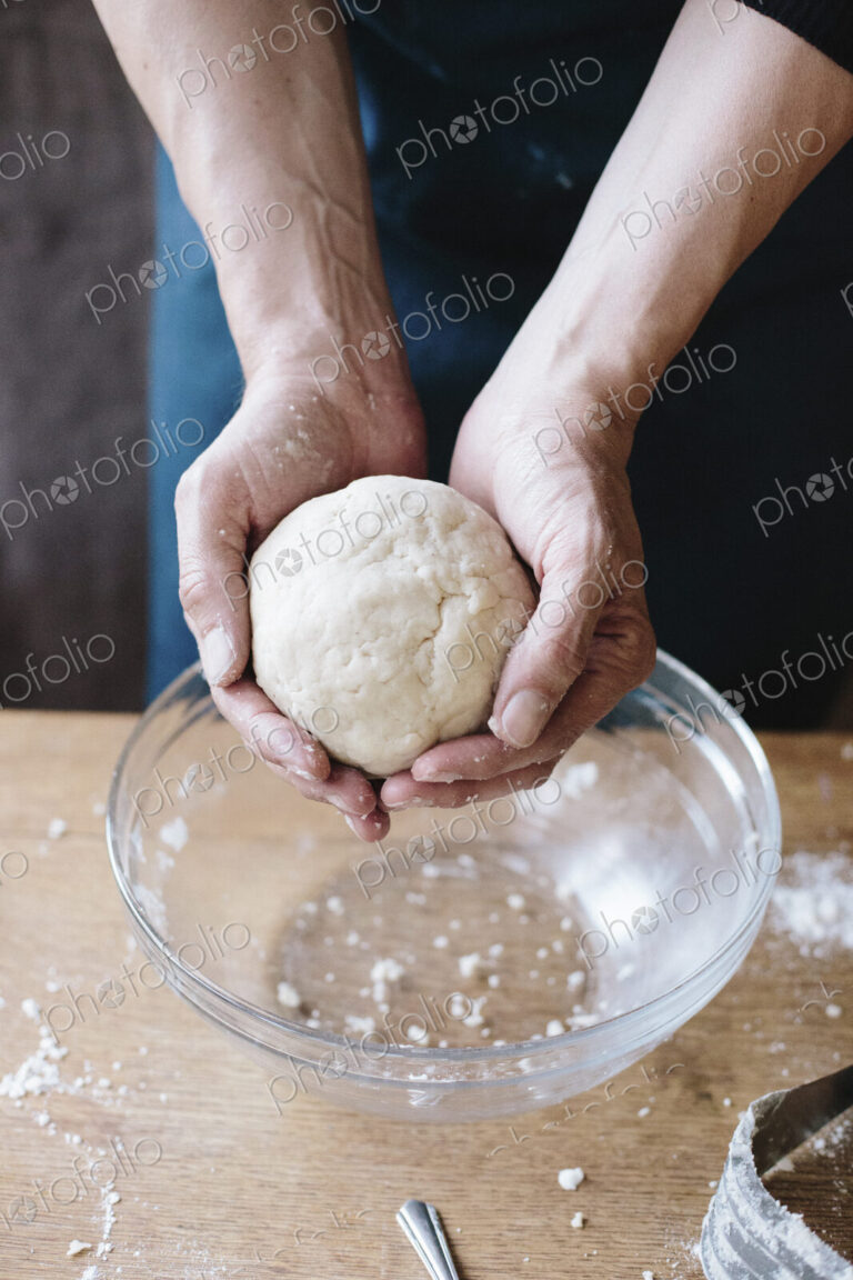 A man baking, holding pastry dough in his hands.