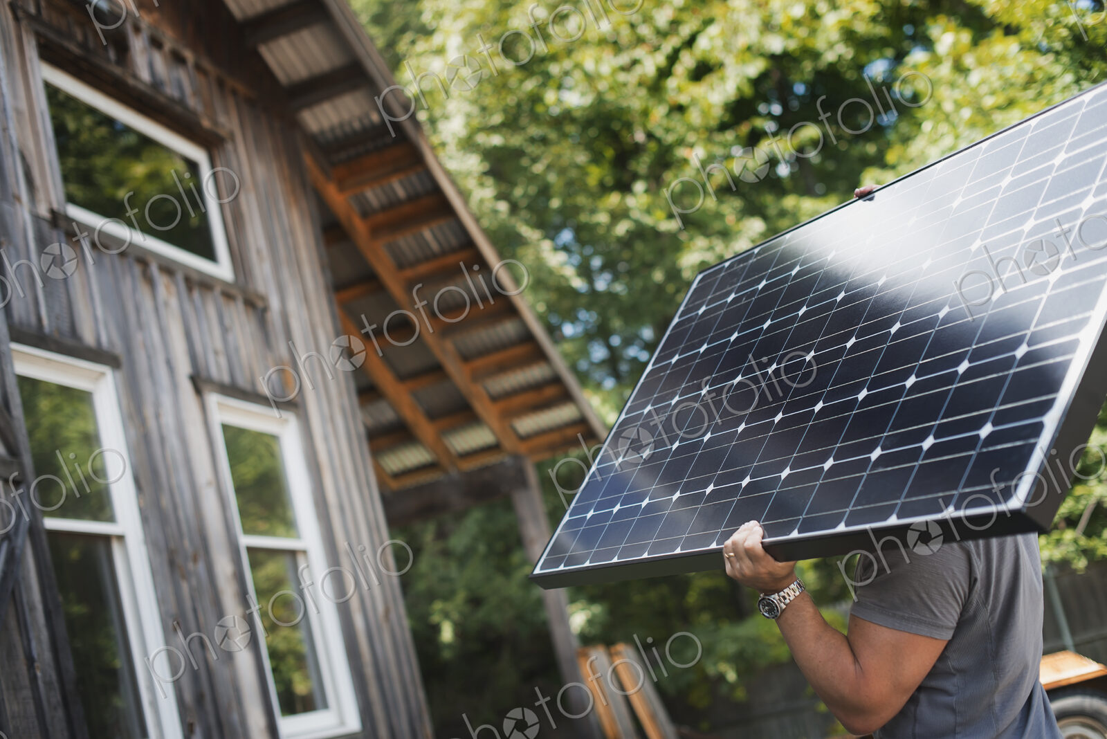 A man carrying a solar panel on a green construction site, working on a green building…