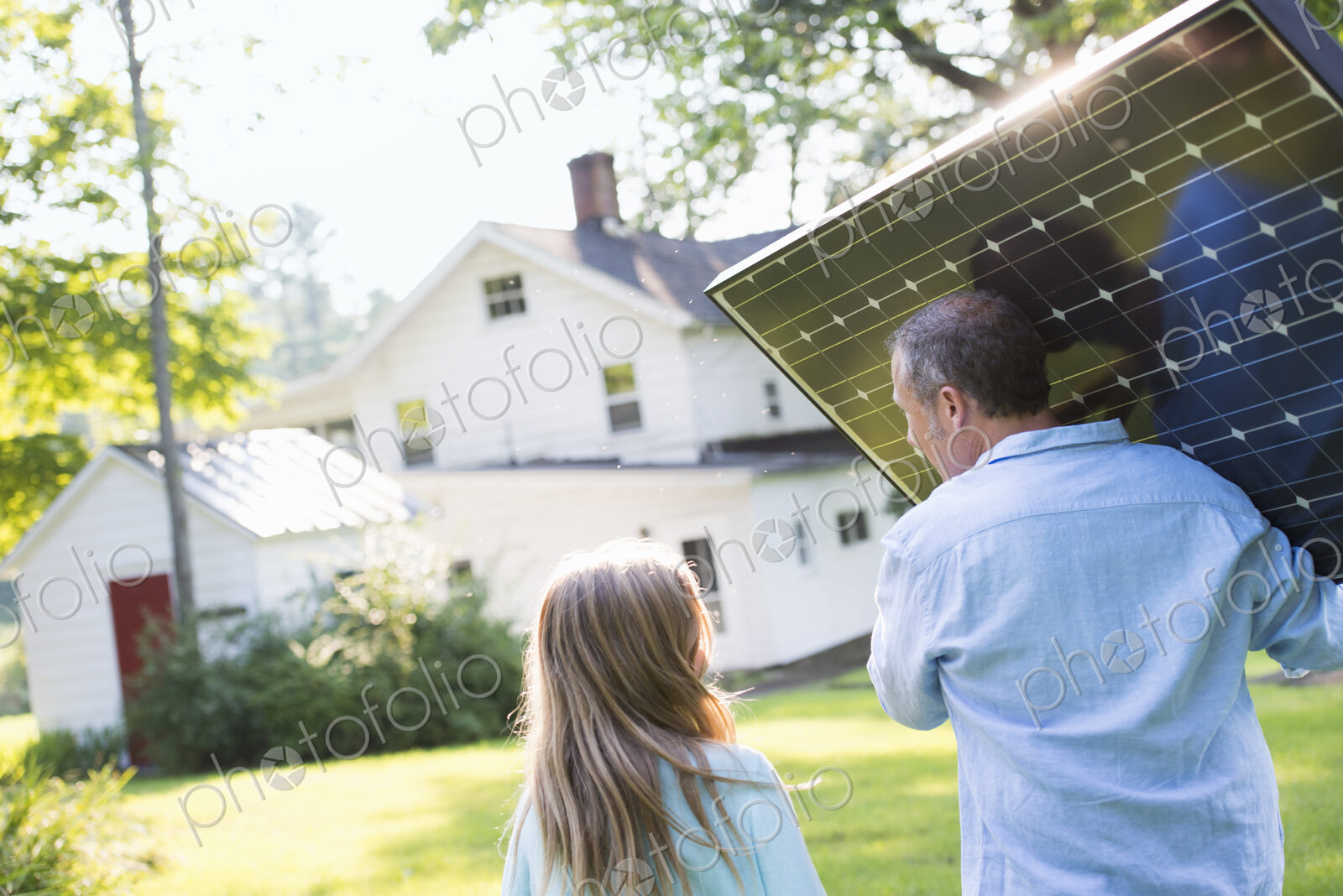 A man carrying a solar panel towards a building under construction.