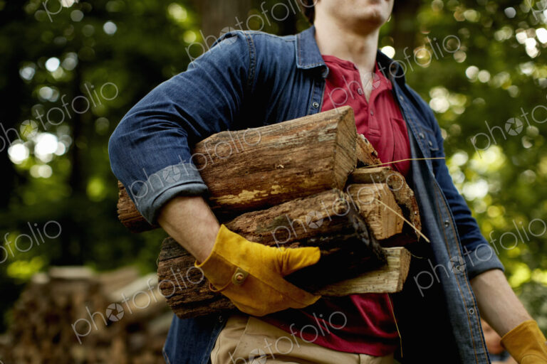 A man carrying a stack of logs under his arm.