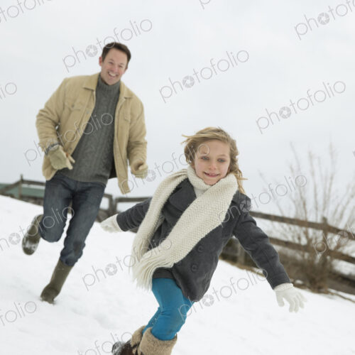 A man chasing a young girl in the snow. Farm in winter. A man chasing a young girl in the snow. Farm in winter.