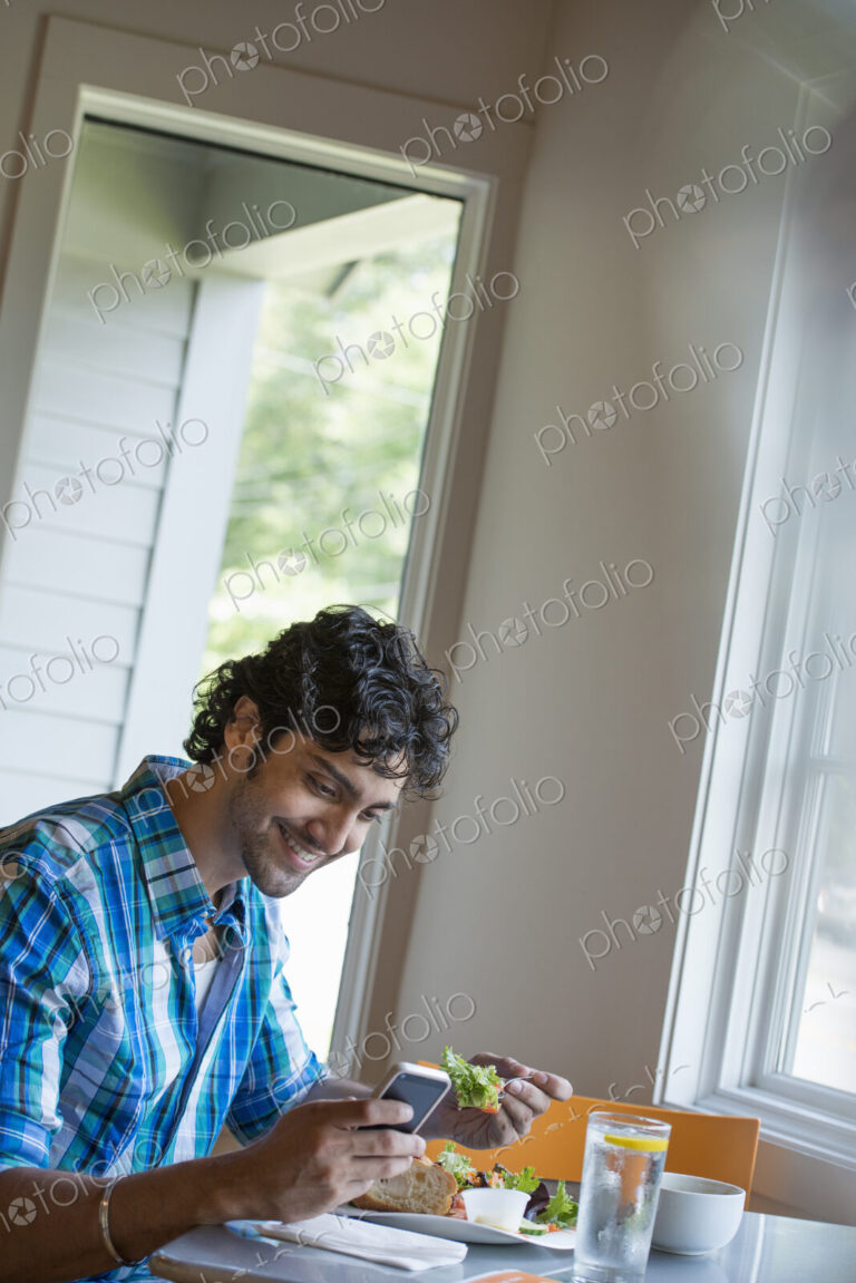 A man checking his phone at a cafe table.