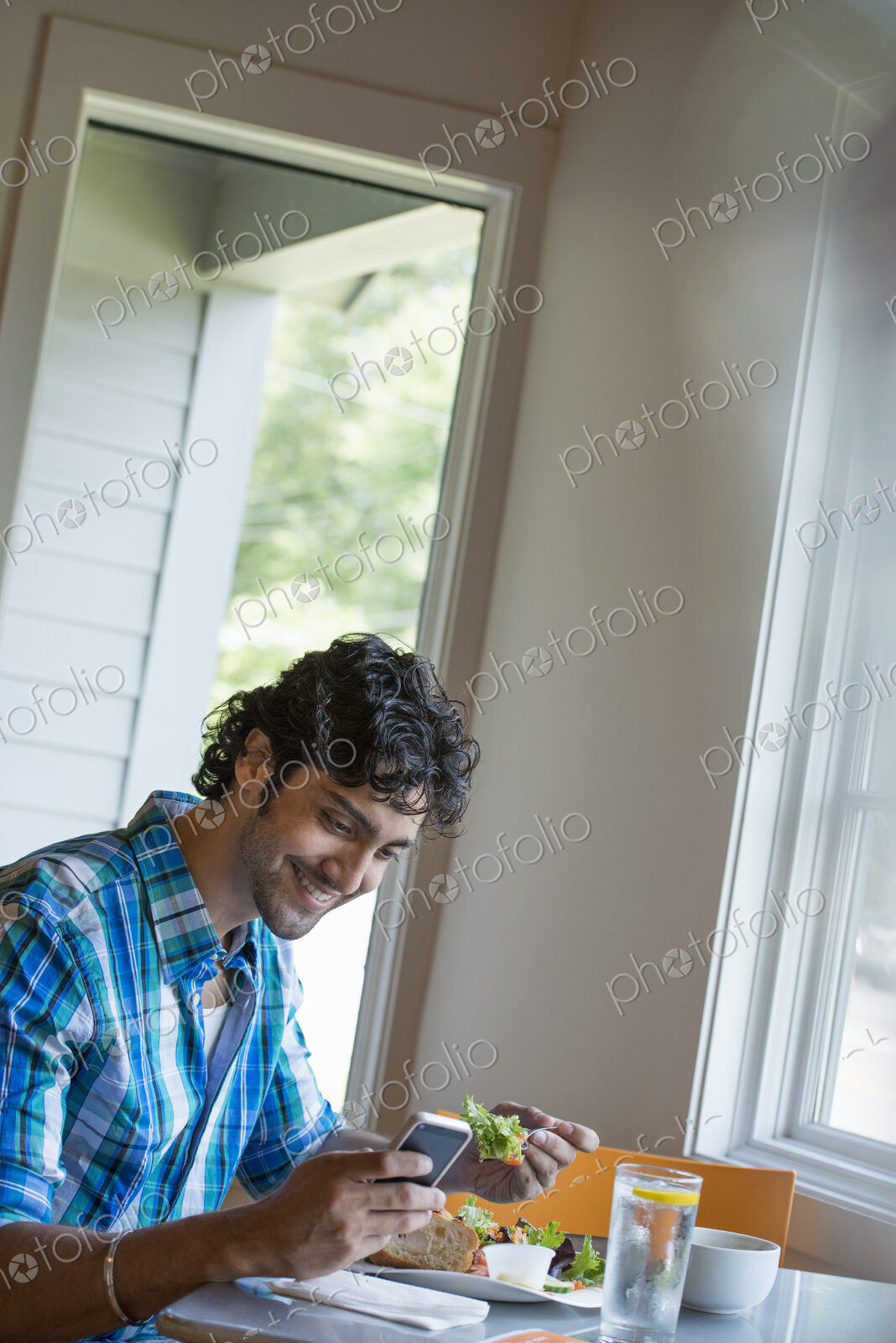 A man checking his phone at a cafe table.