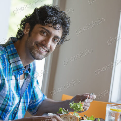 A man checking his phone at a cafe table.