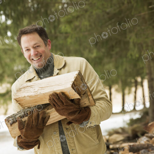 A man collecting firewood, logs for the fire, in snow in winter. A man collecting firewood, logs for the fire, in snow in winter.
