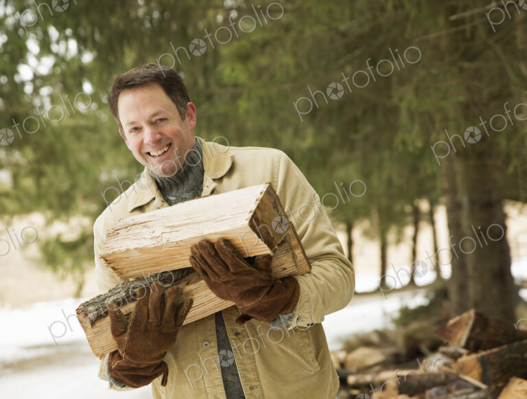 A man collecting firewood, logs for the fire, in snow in winter.