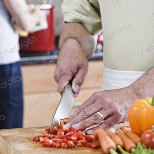 A man cutting vegetables preparing to cook dinner in a kitchen. A man cutting vegetables preparing to cook dinner in a kitchen.