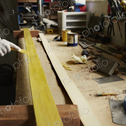 A man examining a piece of wood at a workbench.