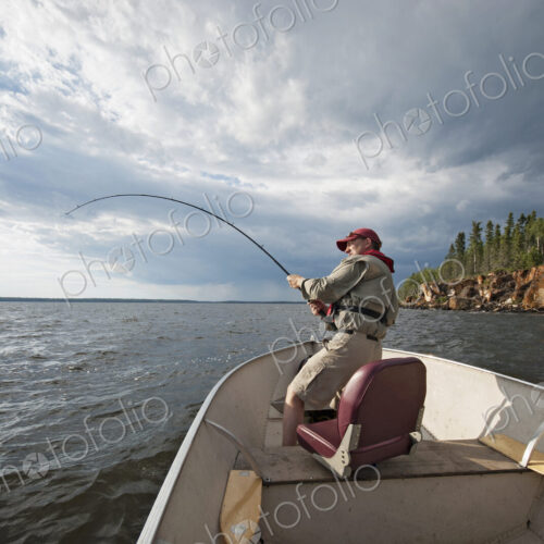 A man fishing from an open boat offshore. A fish on the line. The fishing rod bending… A man fishing from an open boat offshore. A fish on the line. The fishing rod bending…