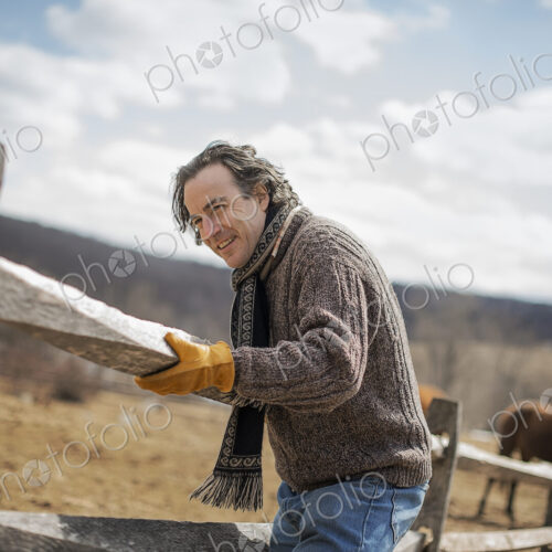 A man fixing a post and rail fence around a horse paddock. A man fixing a post and rail fence around a horse paddock.
