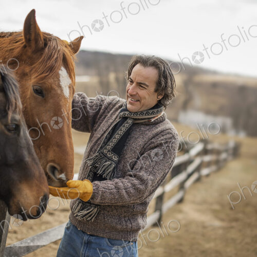A man fixing a post and rail fence around a horse paddock. A man fixing a post and rail fence around a horse paddock.