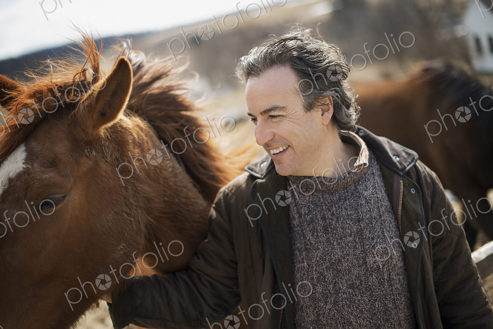 A man fixing a post and rail fence around a horse paddock.