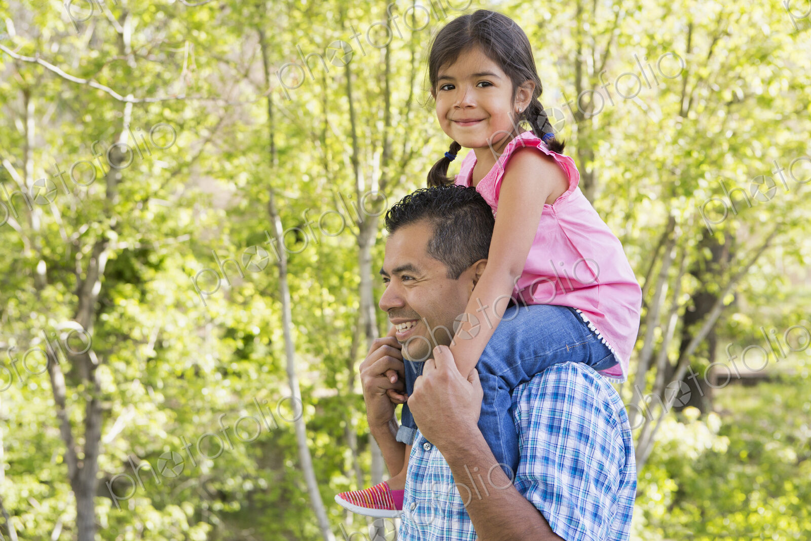 A man giving his daughter a piggyback ride on his shoulders.