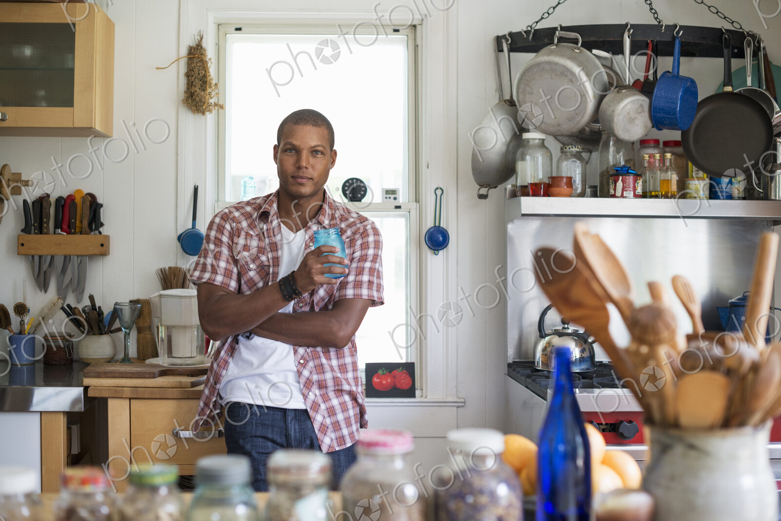 A man holding a drink standing in a farmhouse kitchen.